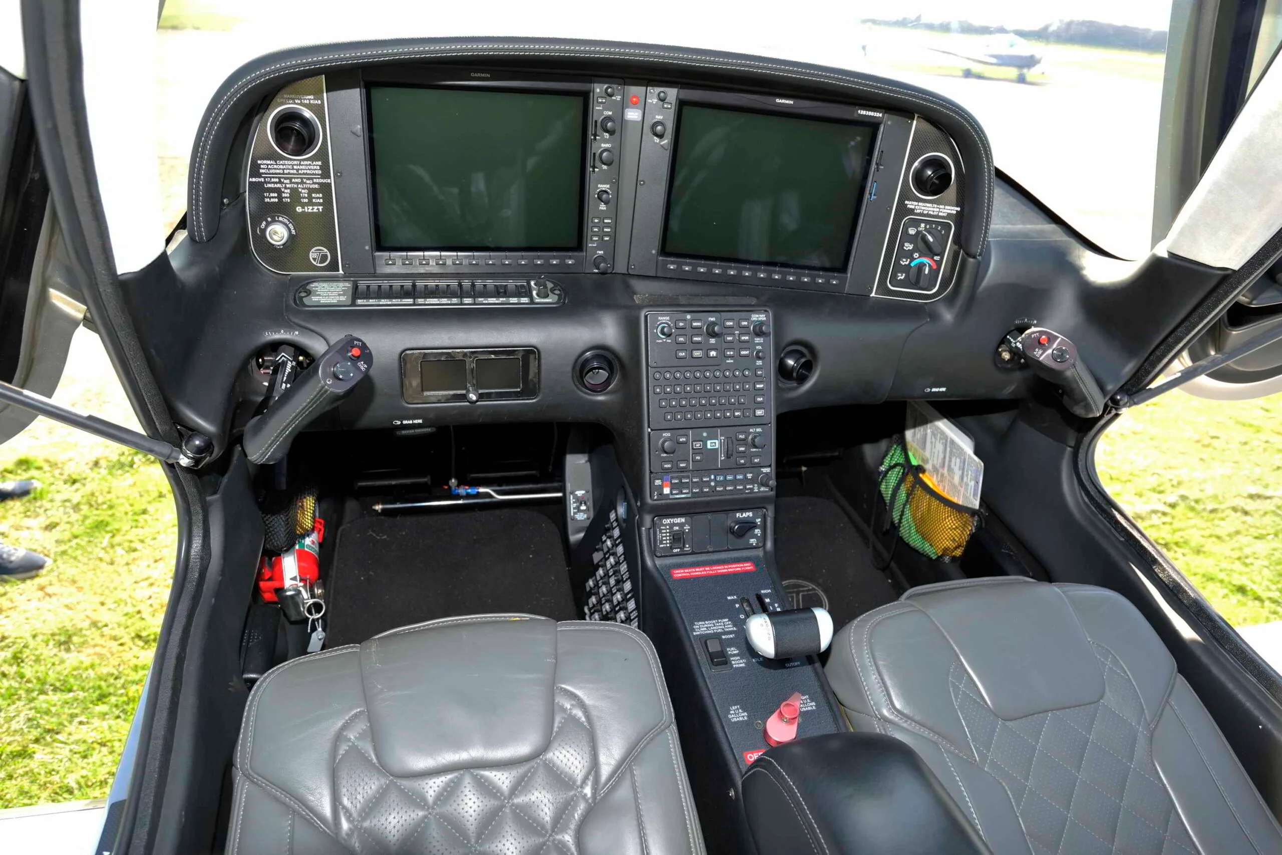 The cockpit of a Cirrus SR22T with dual screens off, showing the control yokes and grey quilted seats.