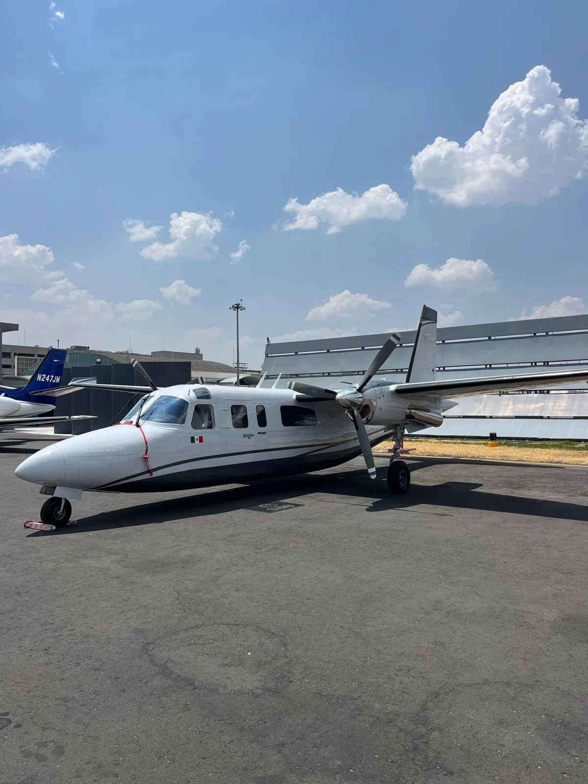 A white and gray aircraft sits on the tarmac under a cloudy sky.