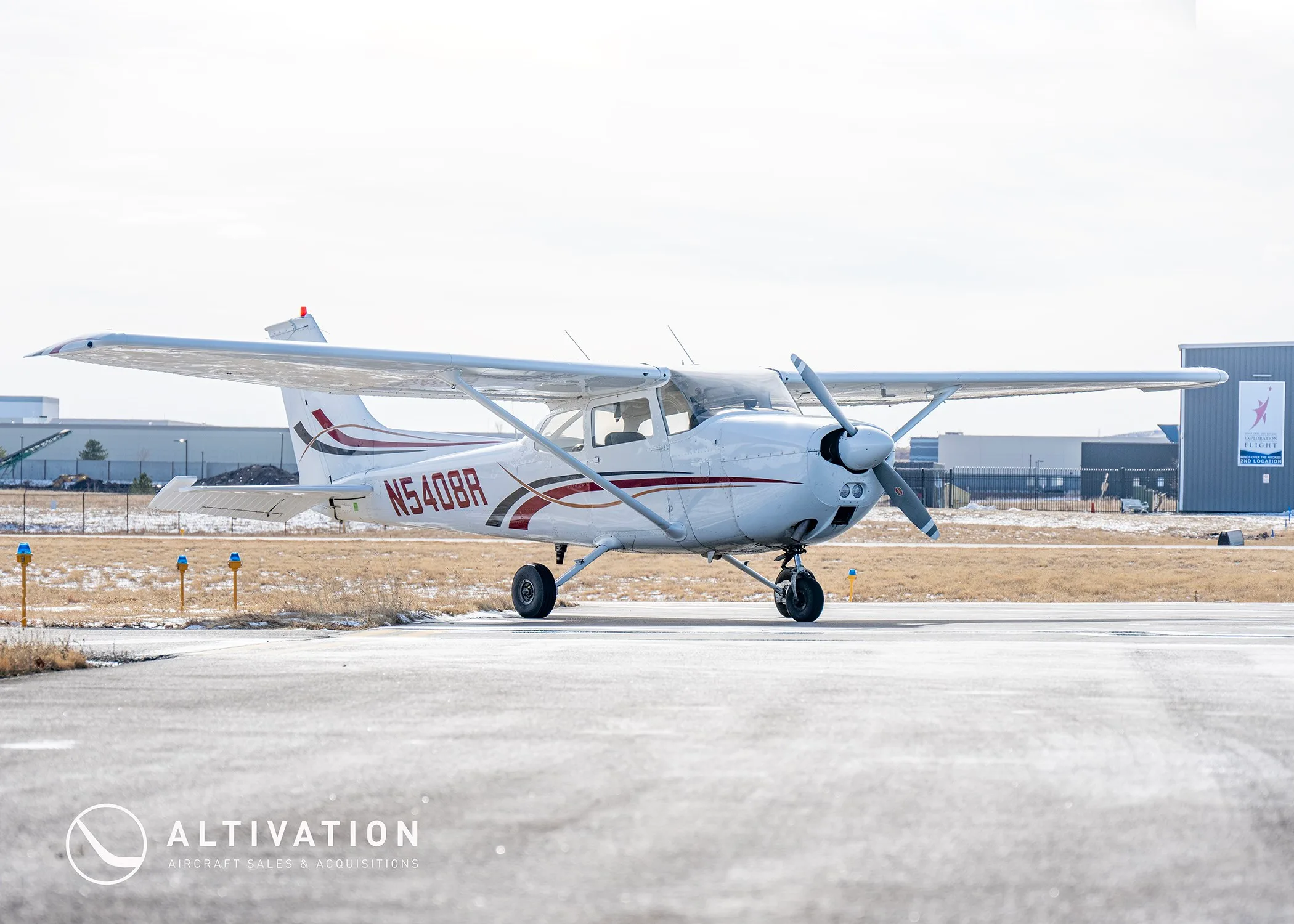 A front-quarter view of a white Cessna 172 with red and black stripes, registration N5408R, parked on an airfield.