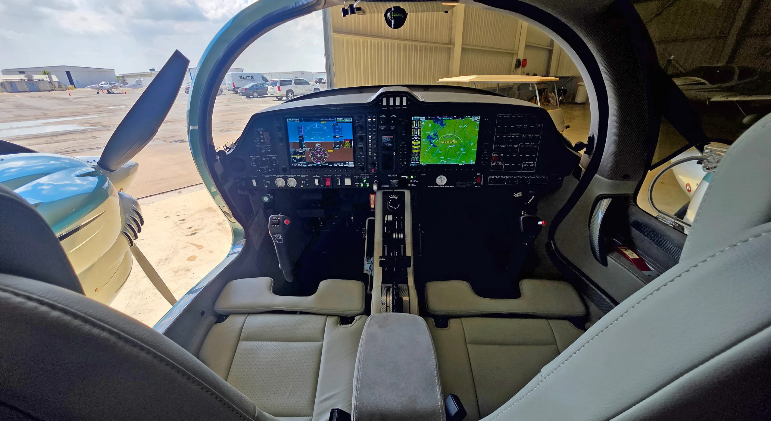 A view from the cabin into the cockpit of a Diamond DA62, showing the instrument panel and light-colored seats.