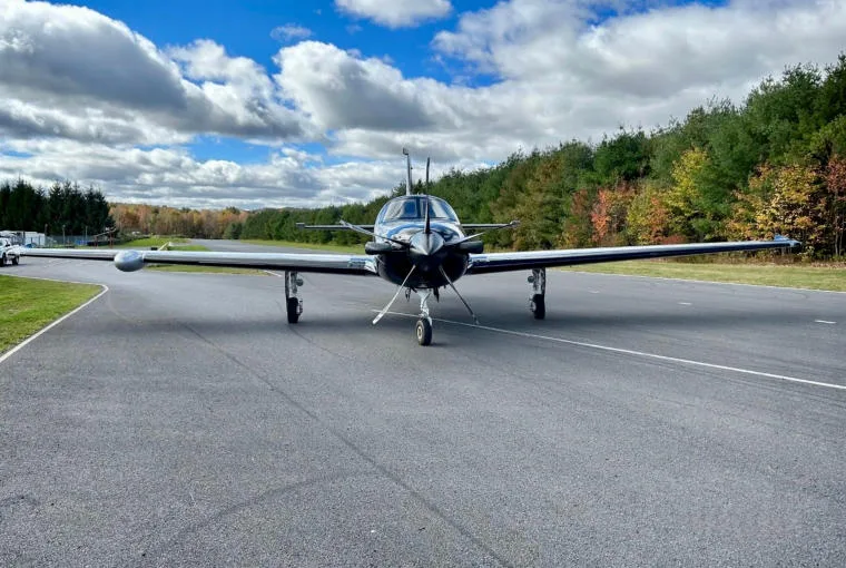 A head-on view of a black and silver Piper M600 SLS aircraft (N63NY) parked on an asphalt runway.