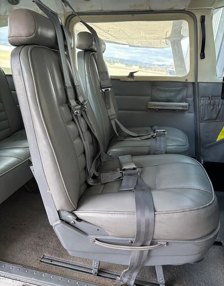 View of the gray front and rear passenger seats with seatbelts inside the aircraft cabin.