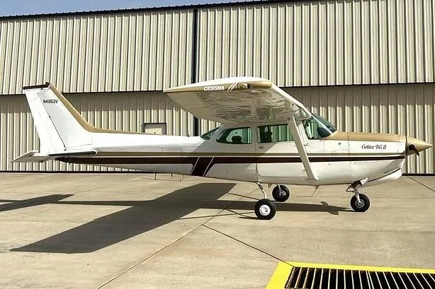 A side view of a white and gold Cessna Cutlass RG II (N4953V) parked on a tarmac.