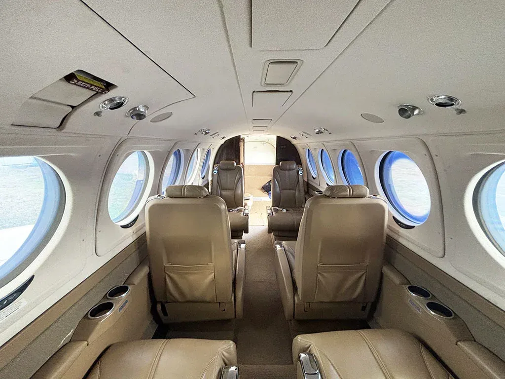 The aircraft's interior cabin with tan leather seats, looking towards the rear of the plane.