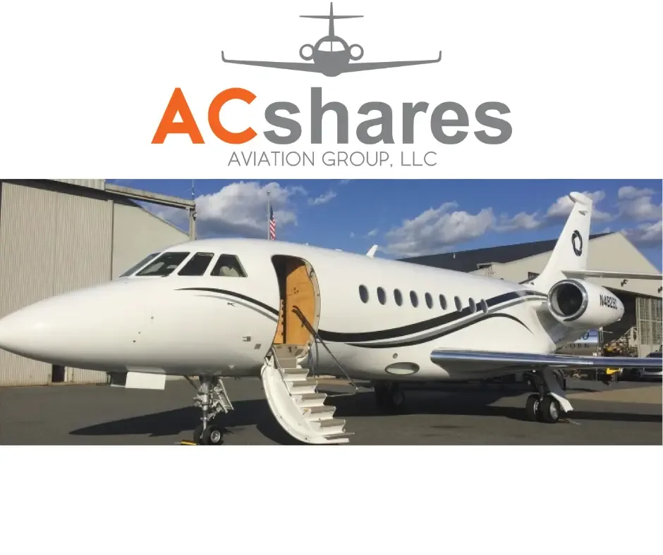 A white business jet with black and grey stripes, door open with stairs, parked on a tarmac in front of a hangar.