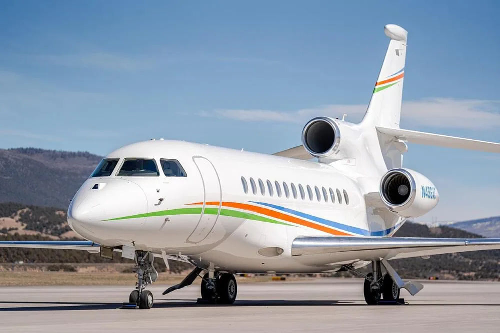 A slightly closer front-side view of the white Dassault Falcon 900EX, registration N496AC, on an airfield.