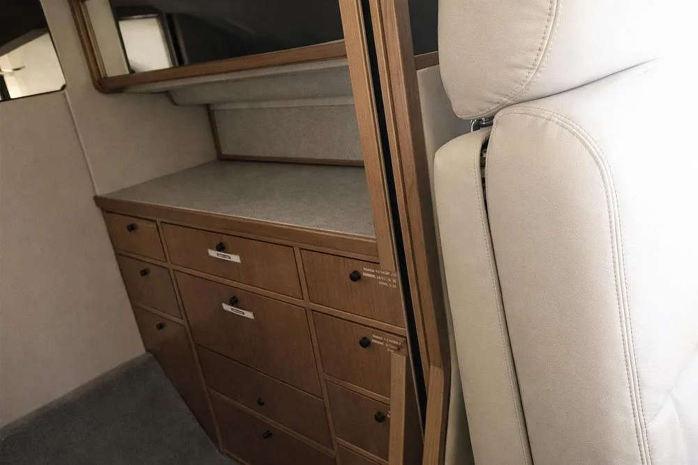 A close-up view of a wooden storage cabinet with multiple drawers inside a private jet cabin.