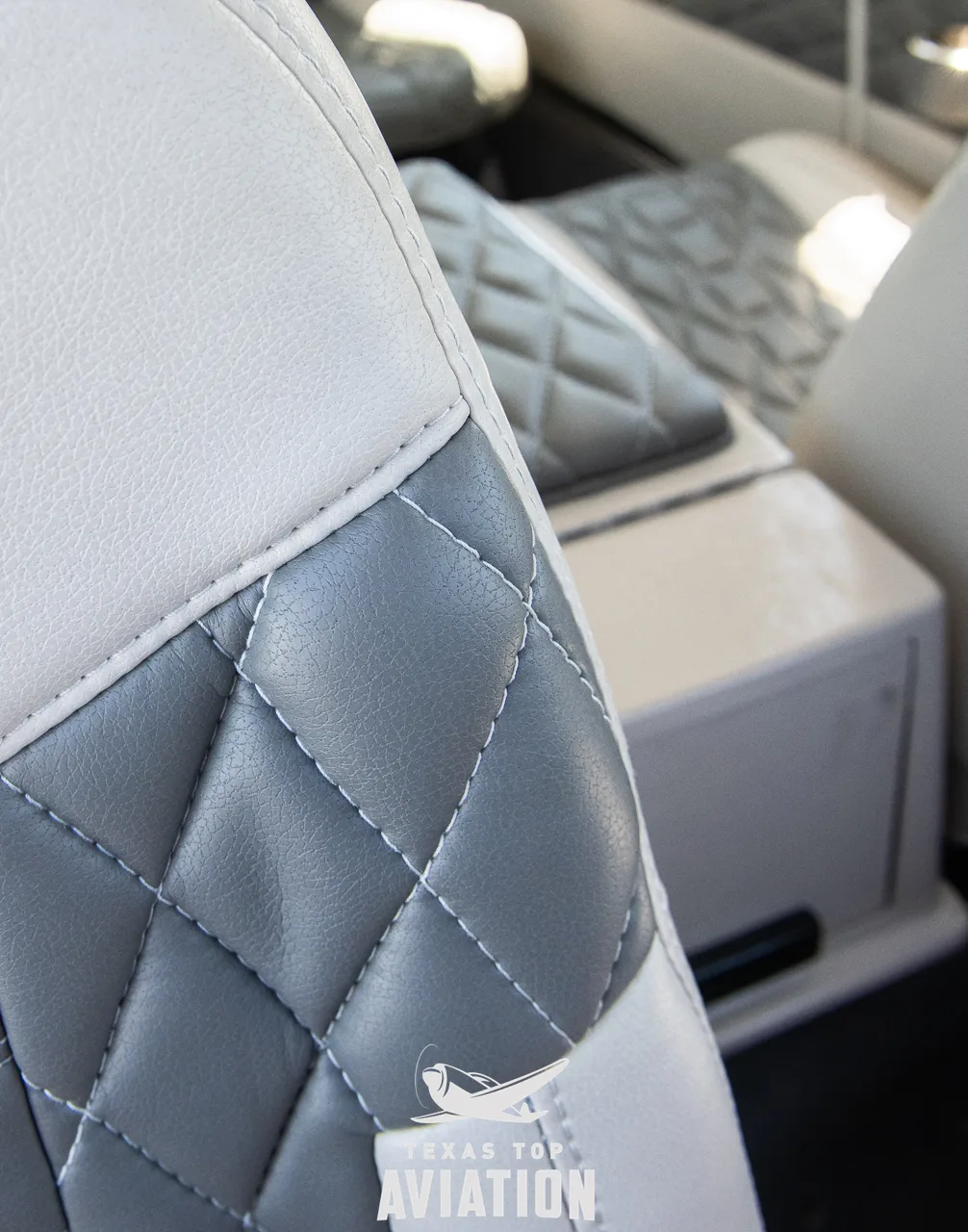 A close-up view of the quilted white and grey seat upholstery in the aircraft cabin.