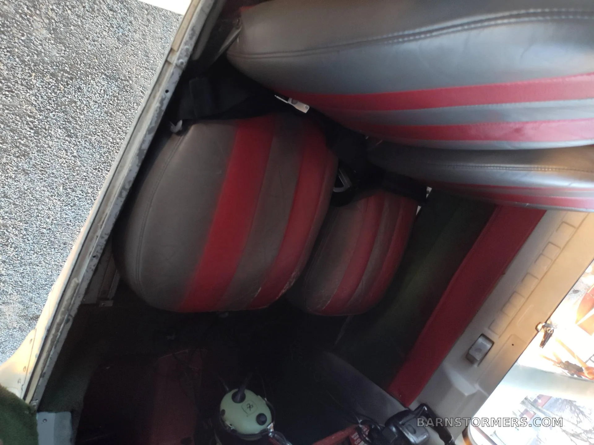 The interior of a light aircraft cabin, showing two grey and red striped seats.