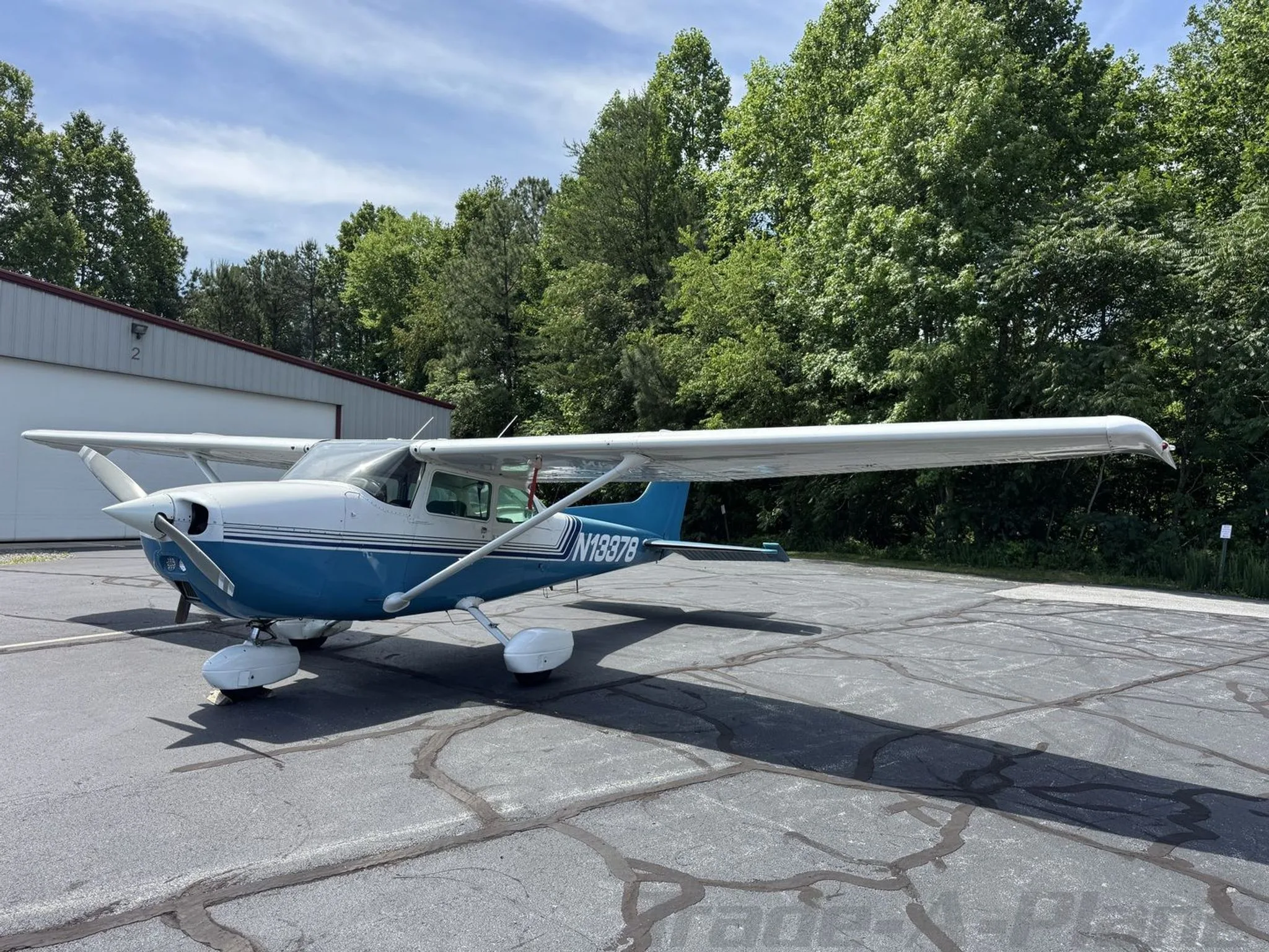 A front-left view of the blue and white Cessna 172 Skyhawk (N13378) parked on an asphalt apron.