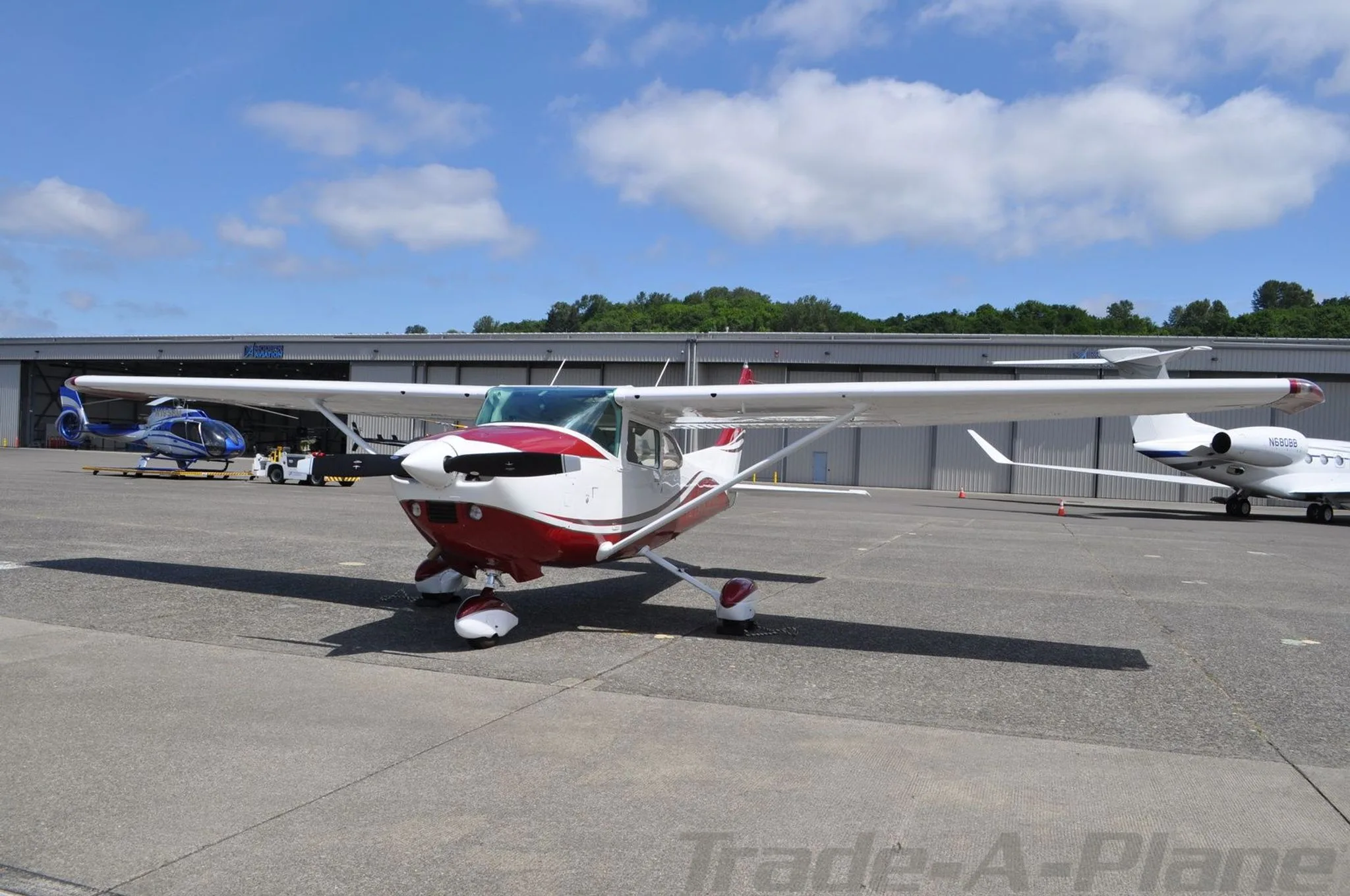 A red and white Cessna N7121S is parked on an airfield, viewed from the front.