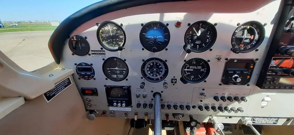 A close-up view of the instrument panel in the cockpit of a red Piper Cherokee 180 (N8325W).