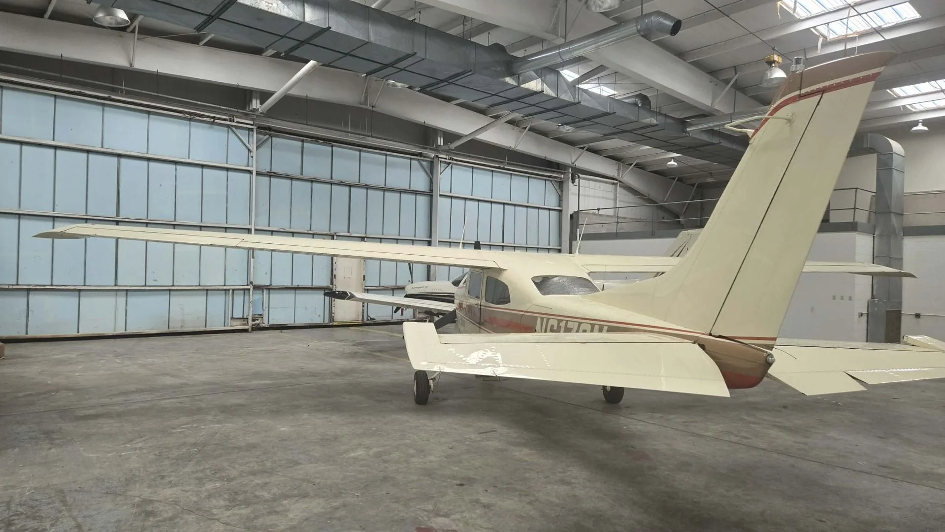 A rear view of the N6170N aircraft, a white and brown high-wing single-engine plane, parked inside a hangar.