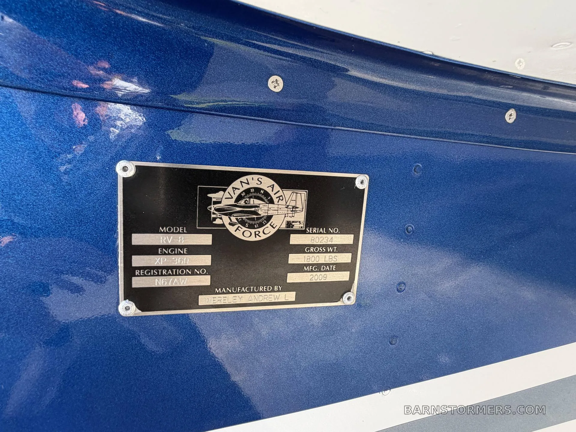 A close-up of a metal data plate on a blue aircraft fuselage, showing "RV-8" model, "XP-360" engine, and manufacturing details.