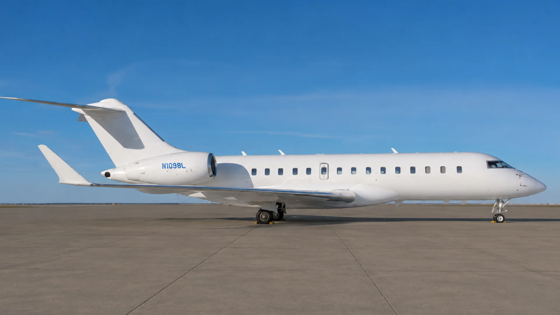 A white Bombardier Global 6000 private jet, tail number N1098L, parked on an airfield under a clear blue sky.