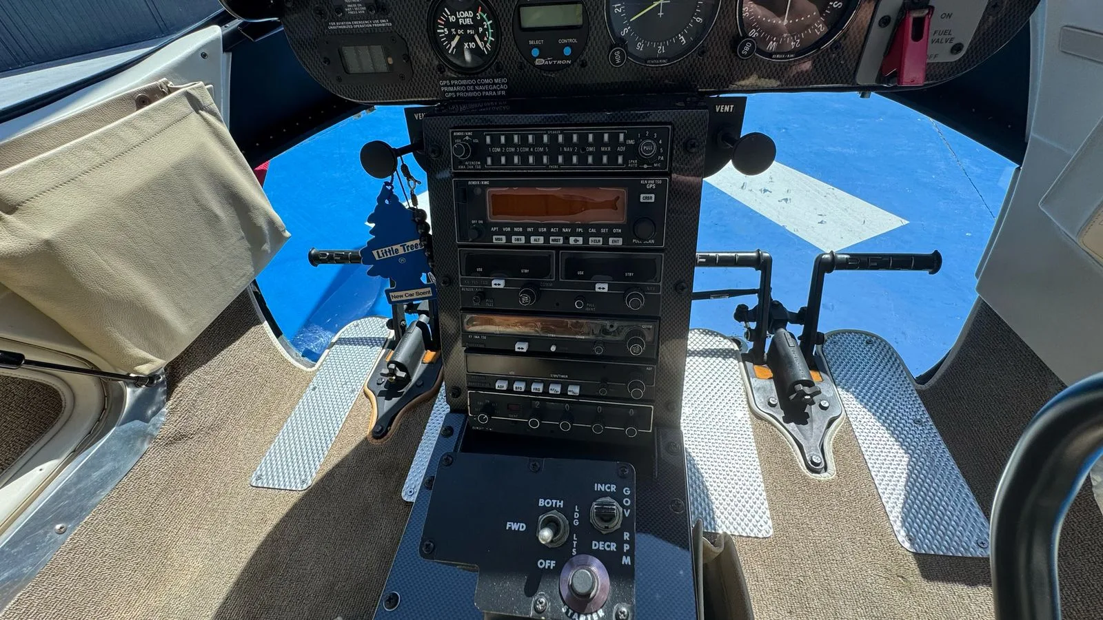 The center console and lower instrument panel of a helicopter, showing radios and flight controls.