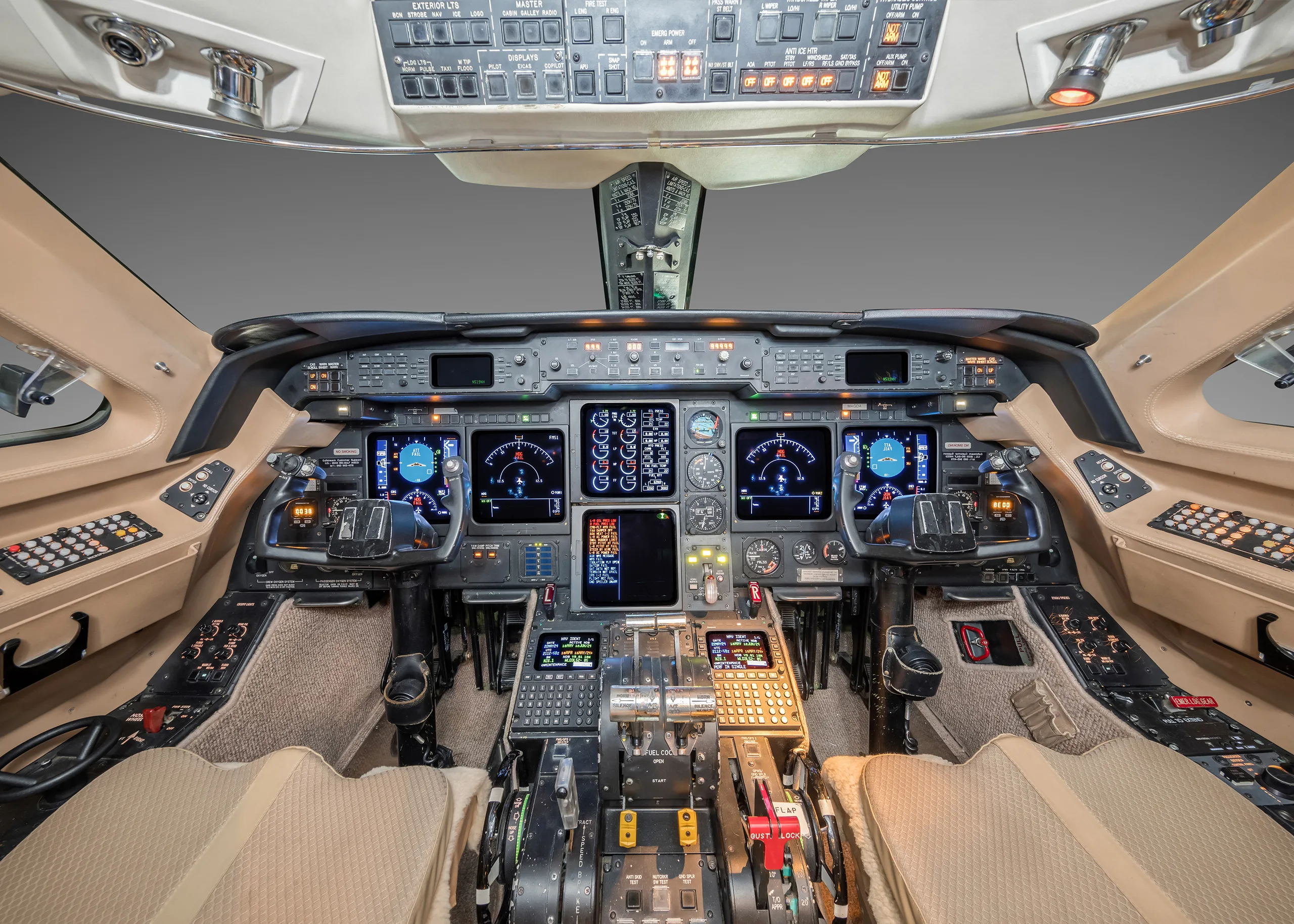 A detailed view of a modern aircraft cockpit with multiple digital displays and control panels.
