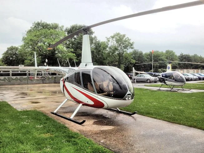 A white Robinson R22 helicopter with red stripes, registration N4502G, parked on a concrete path at an airfield.