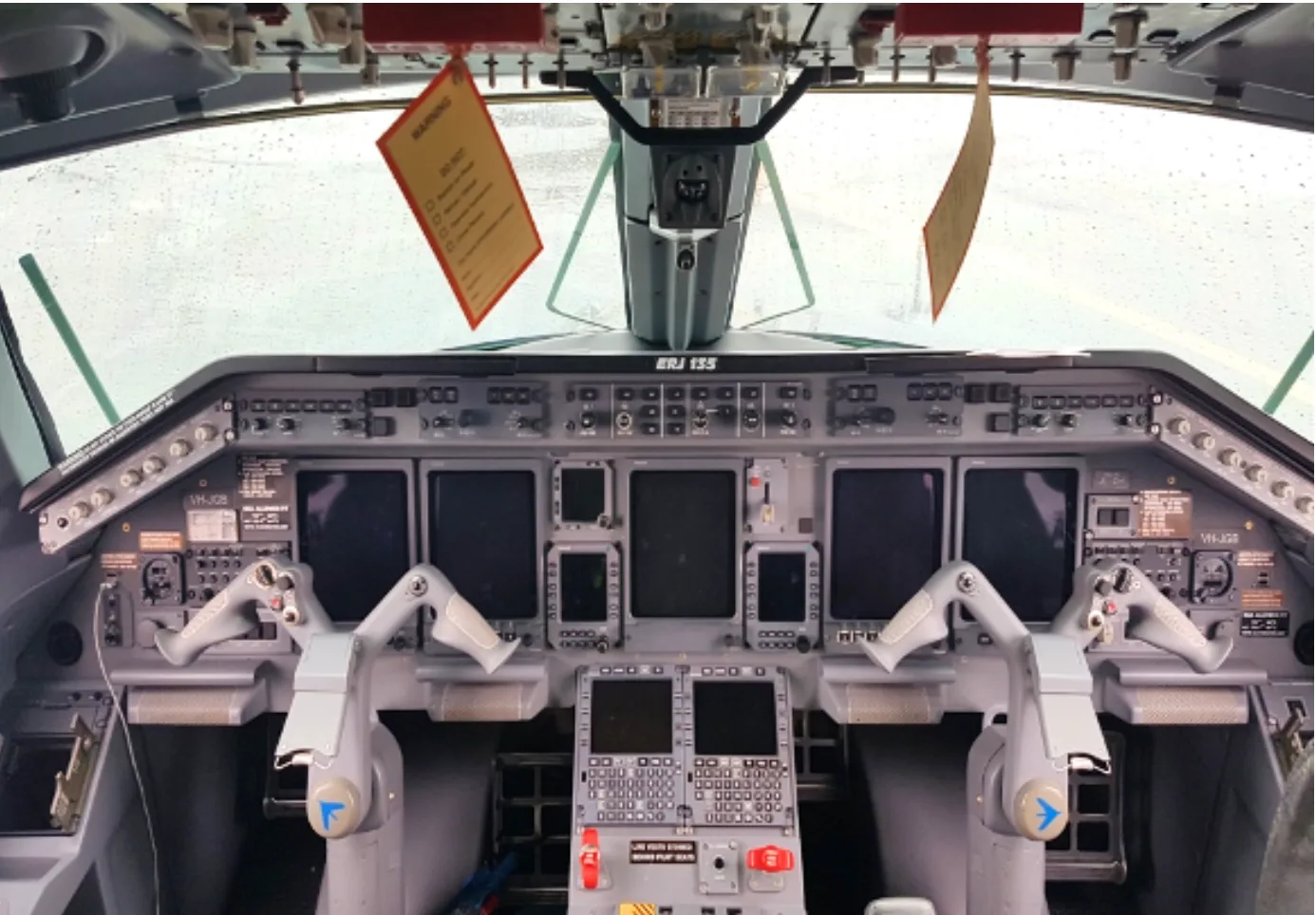 The cockpit of an Embraer ERJ 135 aircraft shows the instrument panel, yokes, and displays.