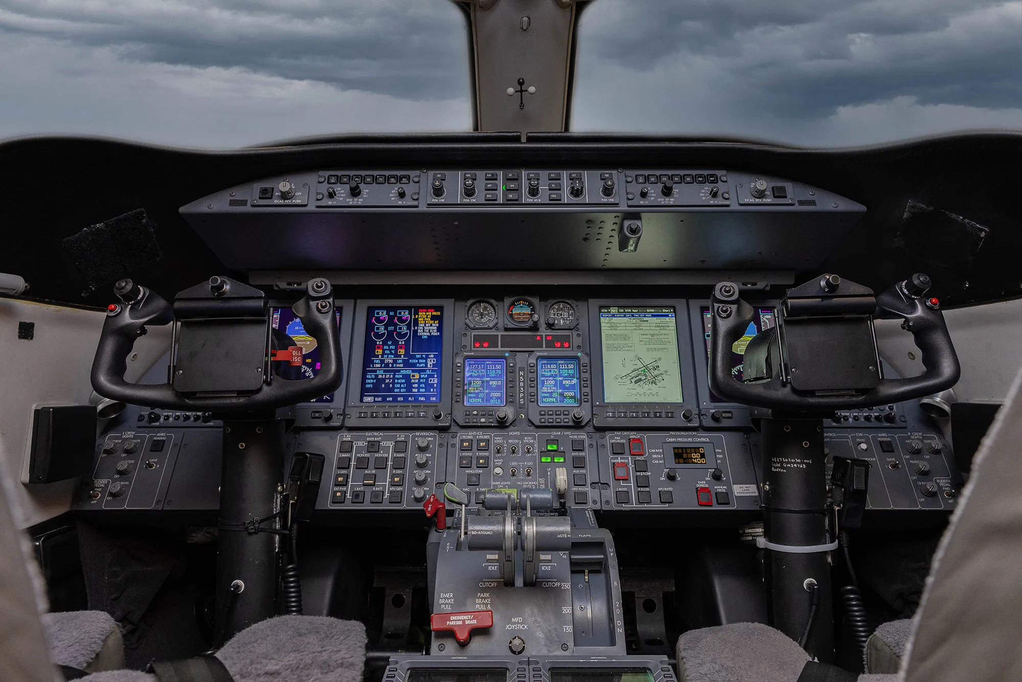 The cockpit of a business jet, featuring multiple digital displays, yokes, and a central control pedestal.