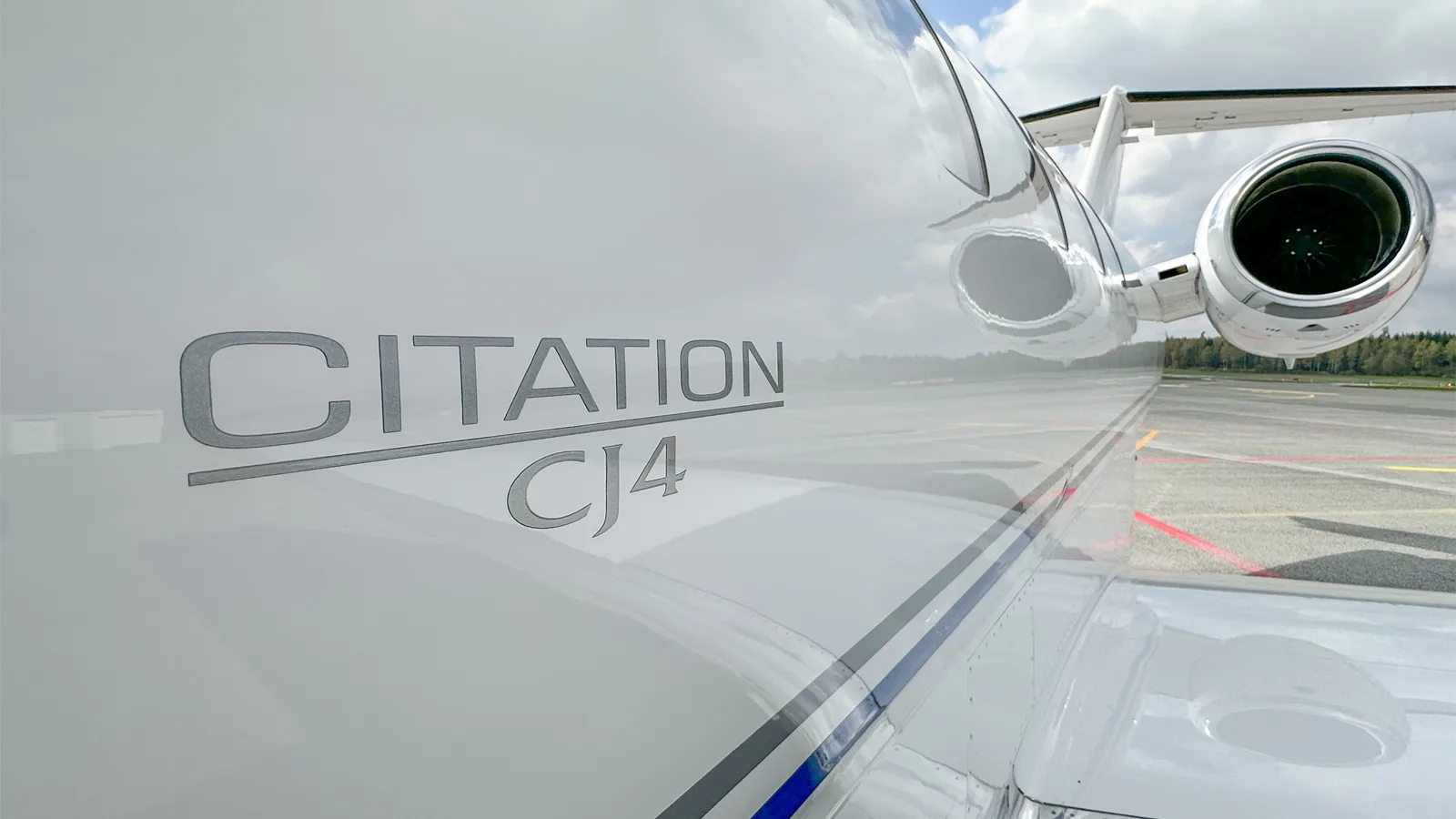 A close-up view of the 'CITATION CJ4' branding on the white fuselage of the aircraft, with an engine visible in the background.