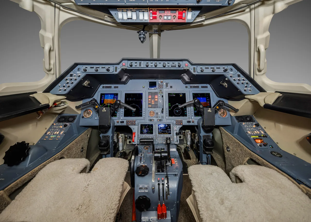 The modern glass cockpit of a business jet with multiple displays and control yokes.