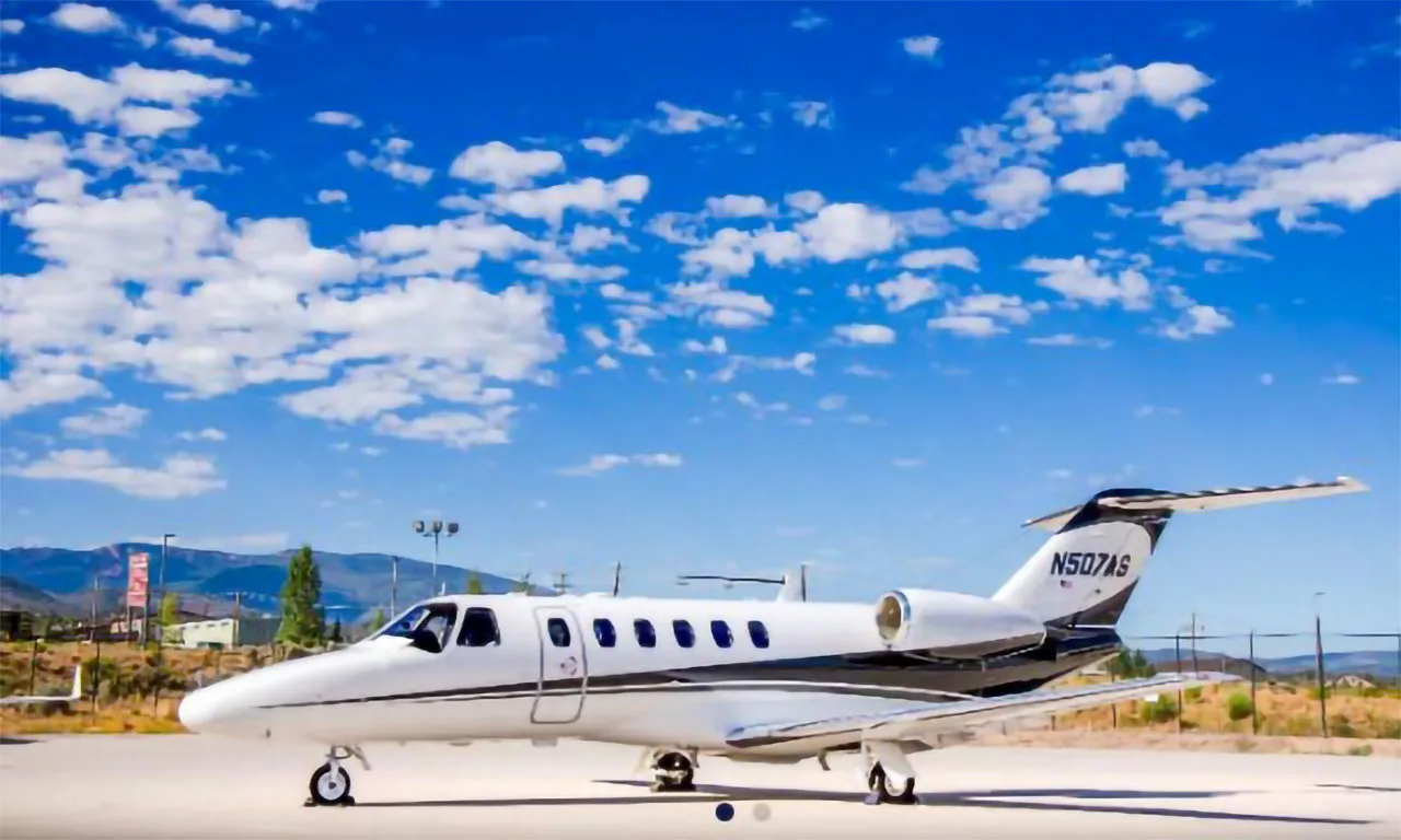 A white and black Cessna Citation business jet, tail number N507AS, parked on an airfield under a blue sky.