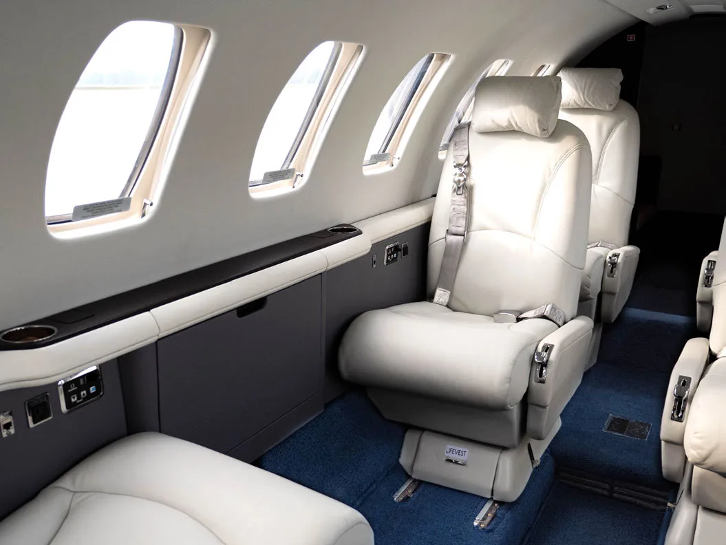 Aircraft interior with white leather seats and side console.