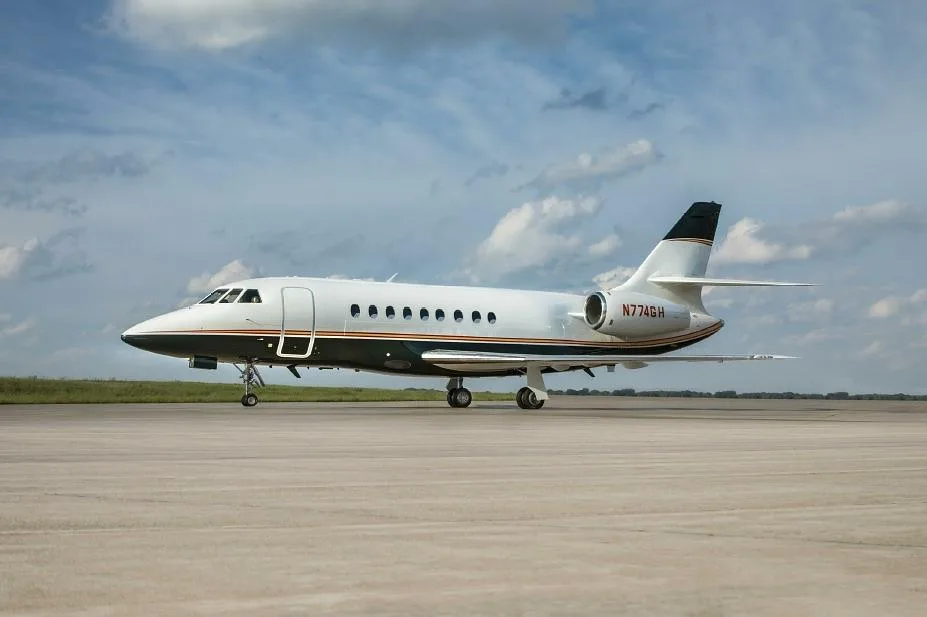 A Dassault Falcon 900EX business jet, registration N774GH, parked on an airfield.