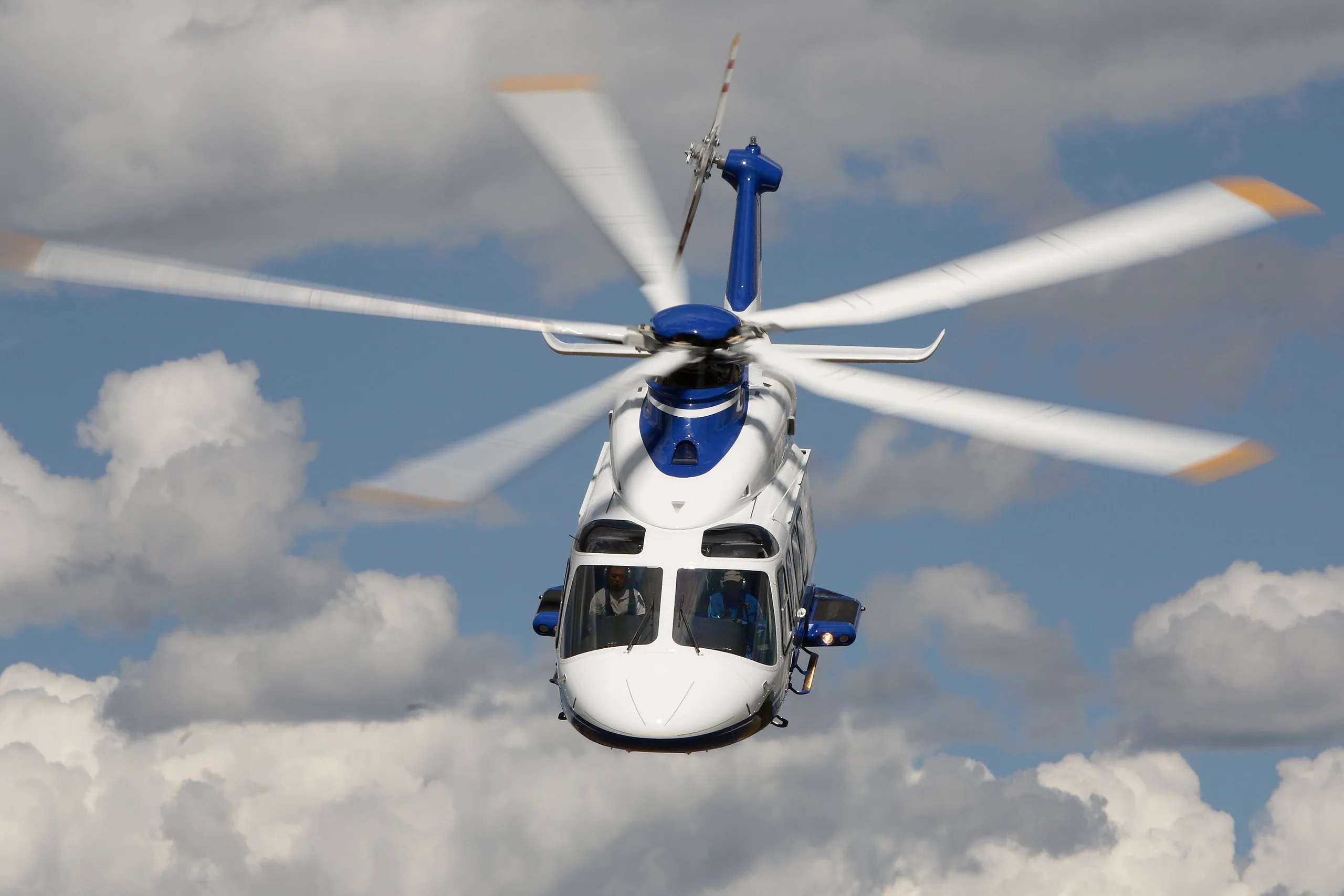 AgustaWestland AW139 helicopter in flight against a cloudy sky.
