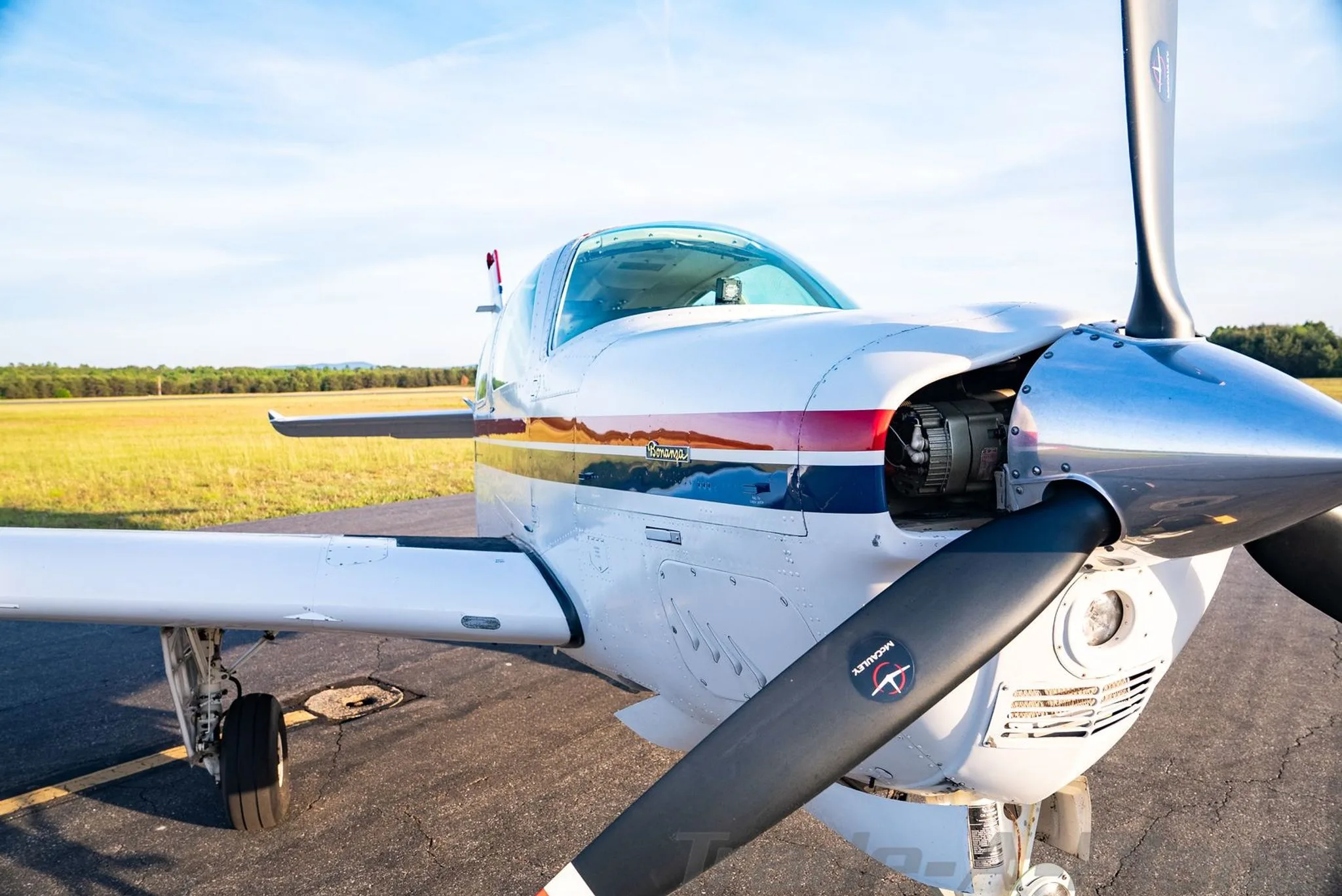 A close-up view of the propeller and nose of the white, red, and blue Beechcraft Bonanza N3108N.