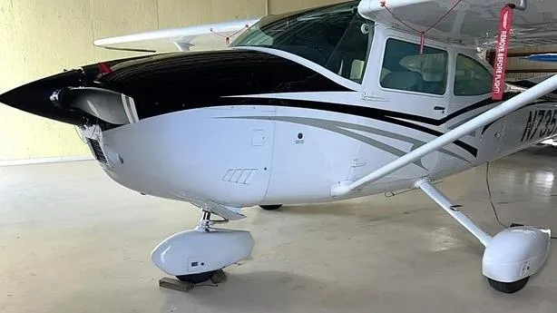 A close-up front view of the white and black Cessna aircraft N735AB, showing the propeller and nose.