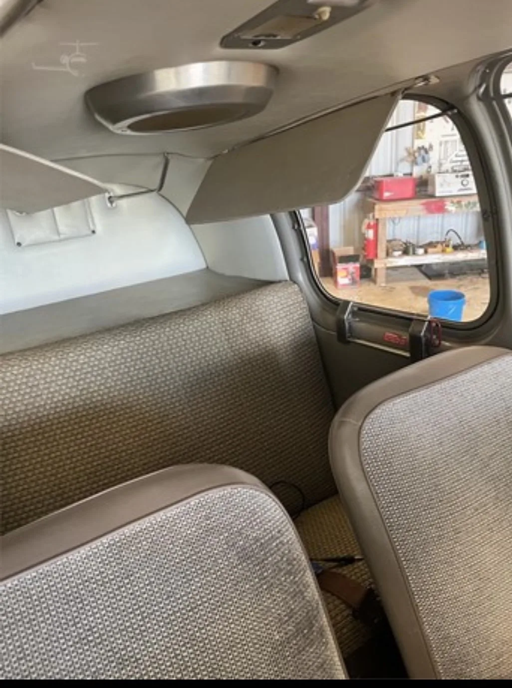 The rear cabin interior of the aircraft, showing two seats with patterned fabric and a cargo area.