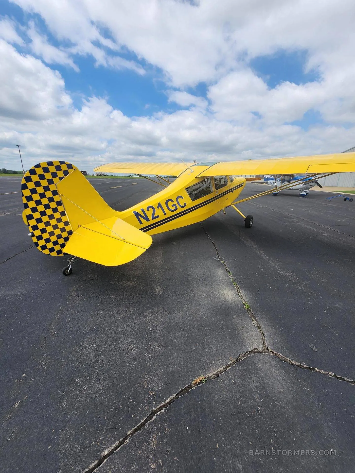 A view of the cockpit of a yellow aircraft with blue seats and a cream-colored instrument panel.