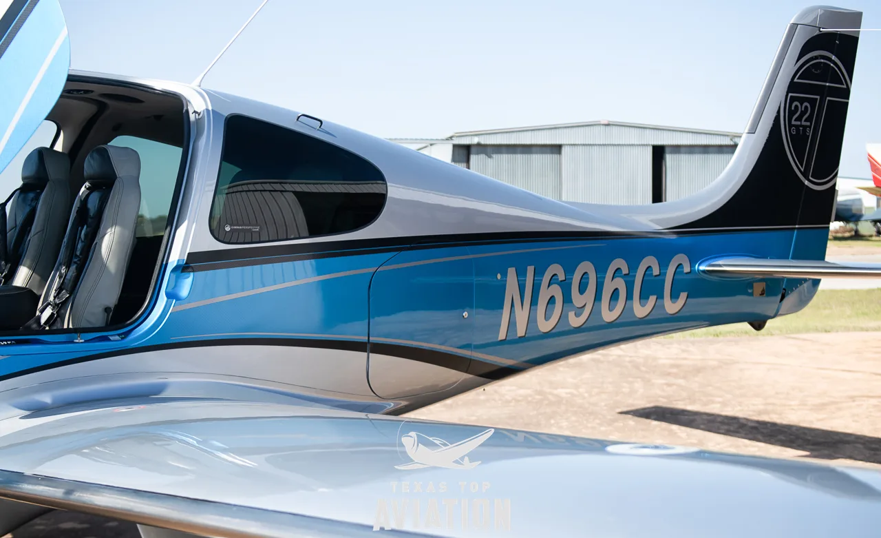 A side view of the Cirrus SR22 aircraft's fuselage, displaying the N-number N696CC and an open passenger door.