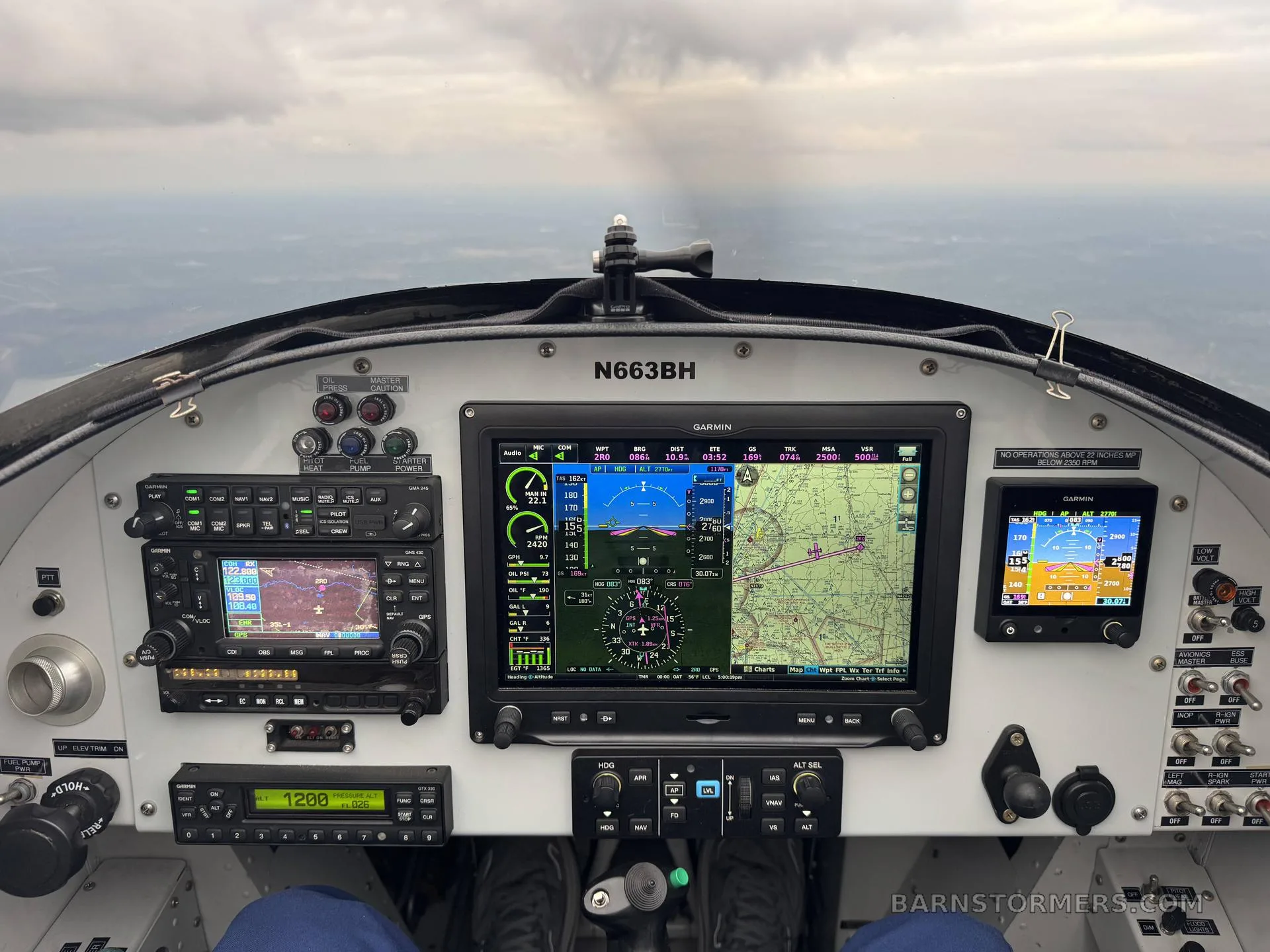 The cockpit of a small aircraft, showing multiple Garmin displays and other instruments, with the registration N663BH visible.