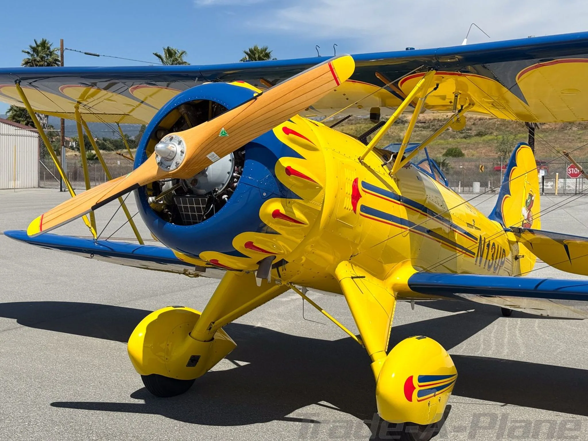 A close-up view of the front fuselage and propeller of a yellow and blue biplane N13UP.