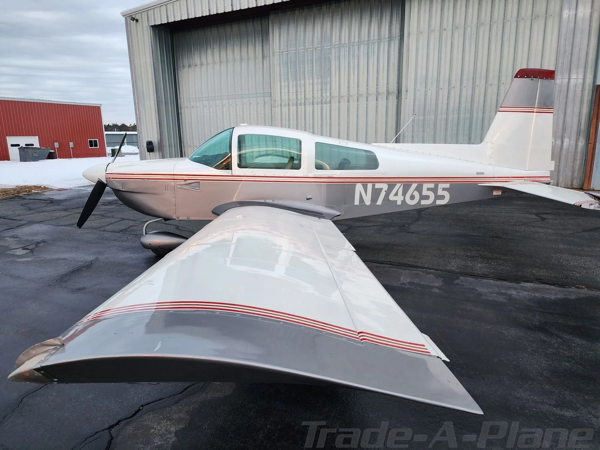 A rear-side view of the white and grey Grumman American aircraft, N74655, showing its wing and tail section.
