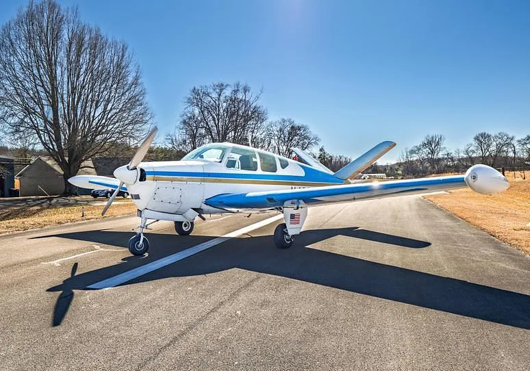 A front-side view of the white and blue single-engine aircraft N4666D with a US flag decal, parked on an asphalt runway.