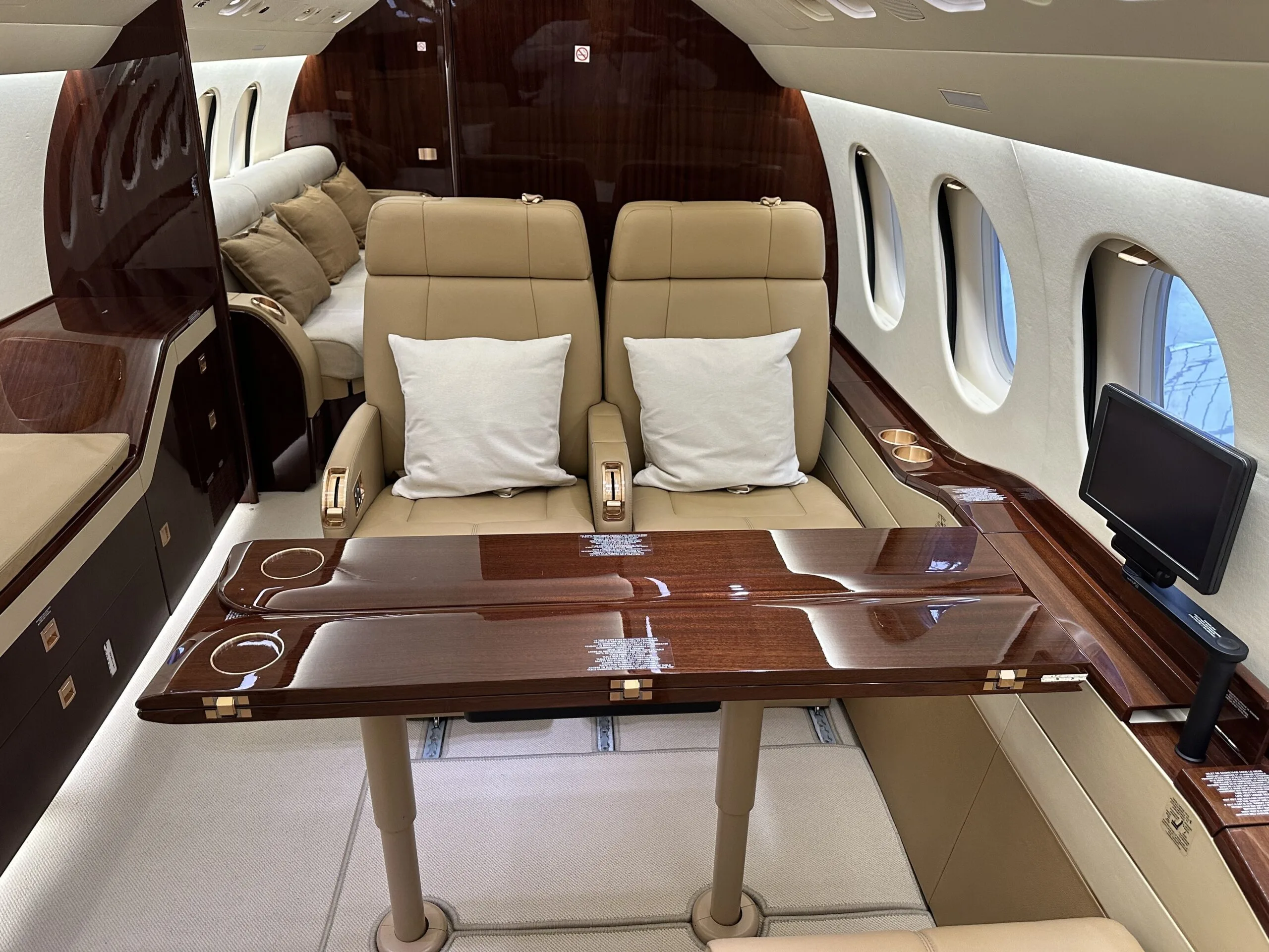 Luxurious aircraft interior with leather seats and a wooden table.