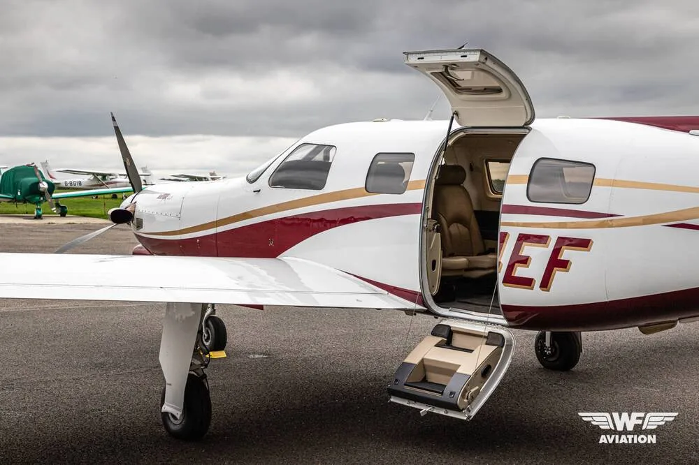 A close-up side view of the N14EF turboprop aircraft with its cabin door open, revealing the tan interior seats.