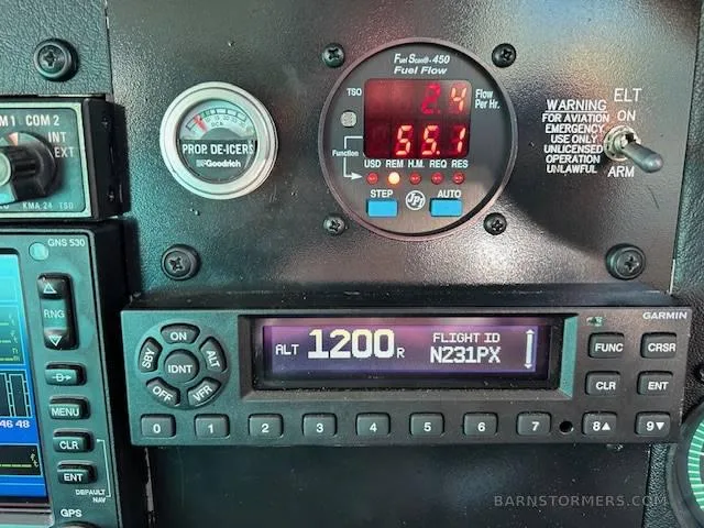 A close-up of the Mooney M20J instrument panel, showing a fuel flow gauge, prop de-icer gauge, and a Garmin transponder displaying "ALT 1200" and "N231PX".