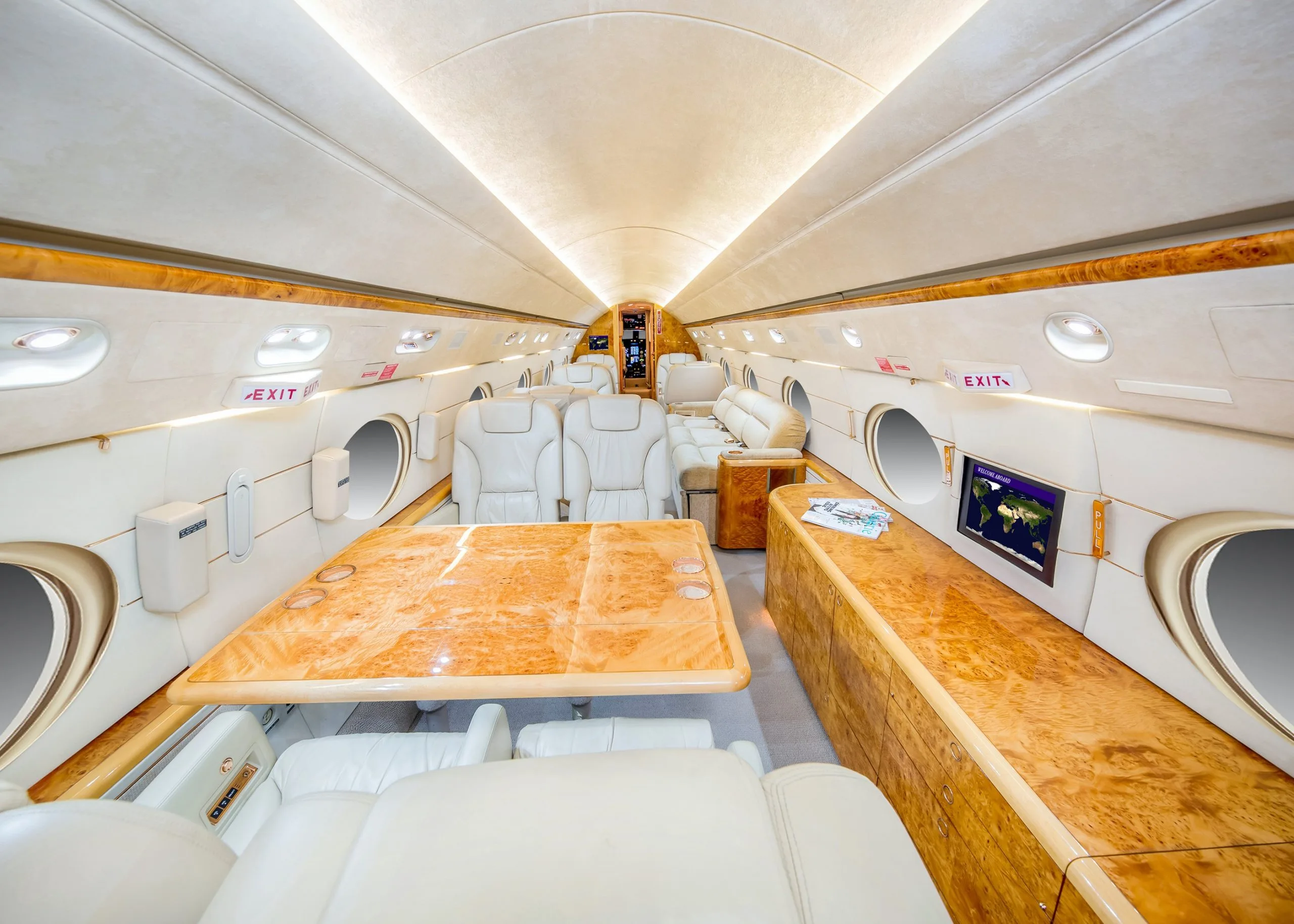 Wide view of the aircraft interior with cream-colored leather seats and wood trim.
