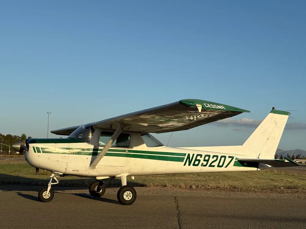 A white and green Cessna N69207 aircraft parked on an airfield at sunset.