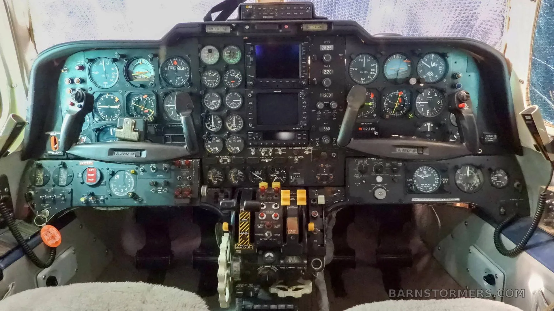 The cockpit instrument panel of a twin-engine aircraft, featuring numerous analog gauges and some digital displays.