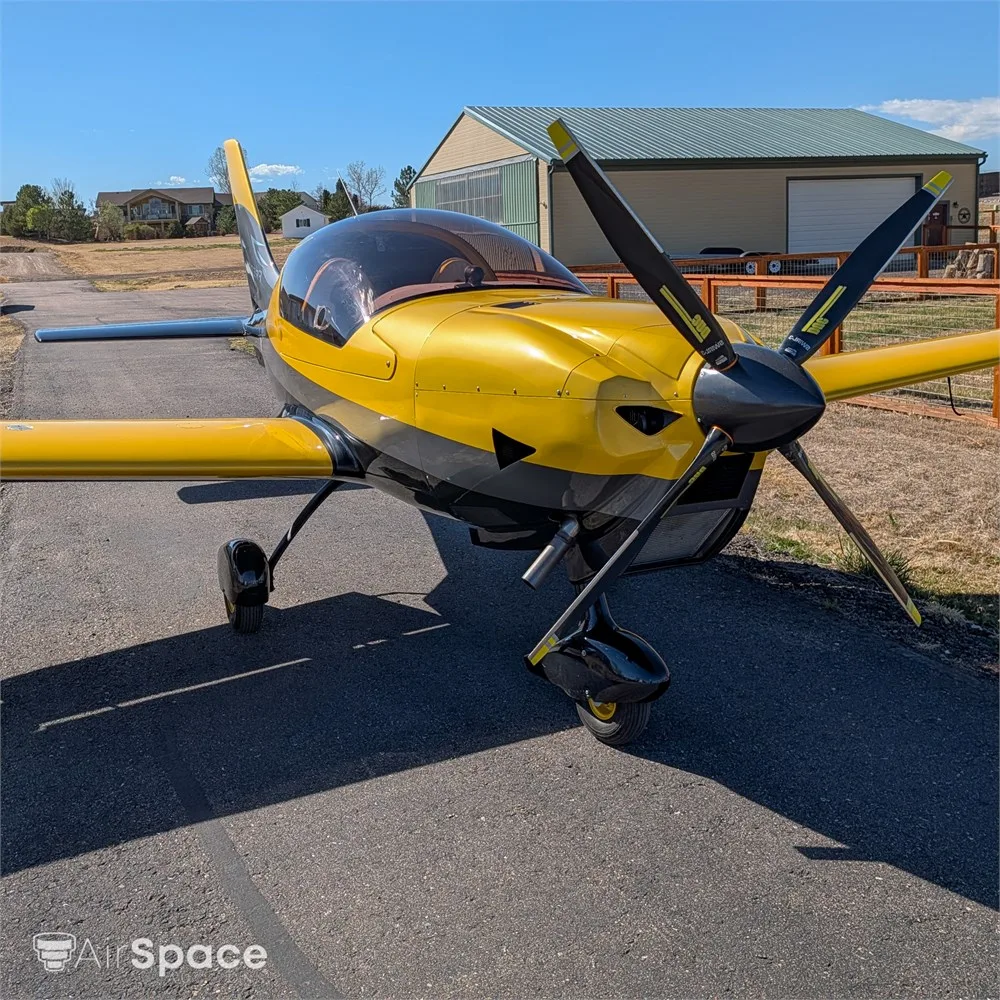 A front-quarter view of a yellow and black Freccia F200 aircraft with a three-bladed propeller, parked on an asphalt ramp.