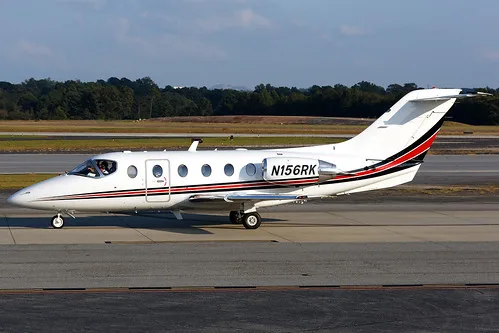 Side view of a white Eclipse 500 aircraft with registration N156RK on the tarmac.