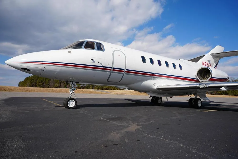 A low-angle view of the front-right side of the white business jet N69FR, showing its cockpit and engine.