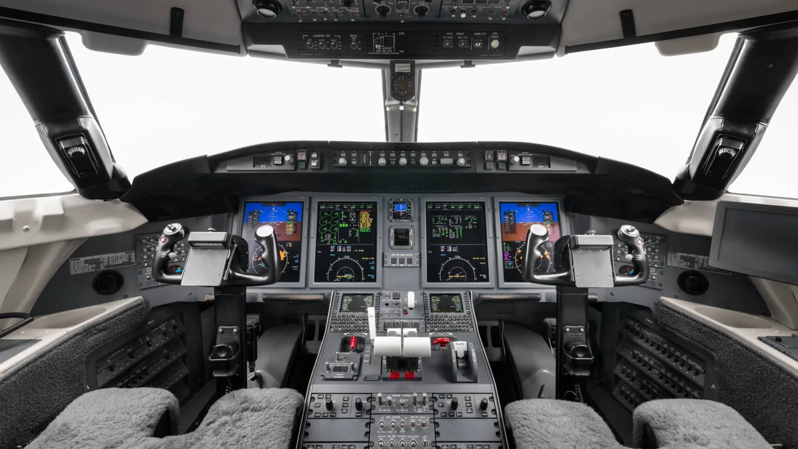 The modern cockpit of a business jet, featuring multiple digital displays and control yokes.