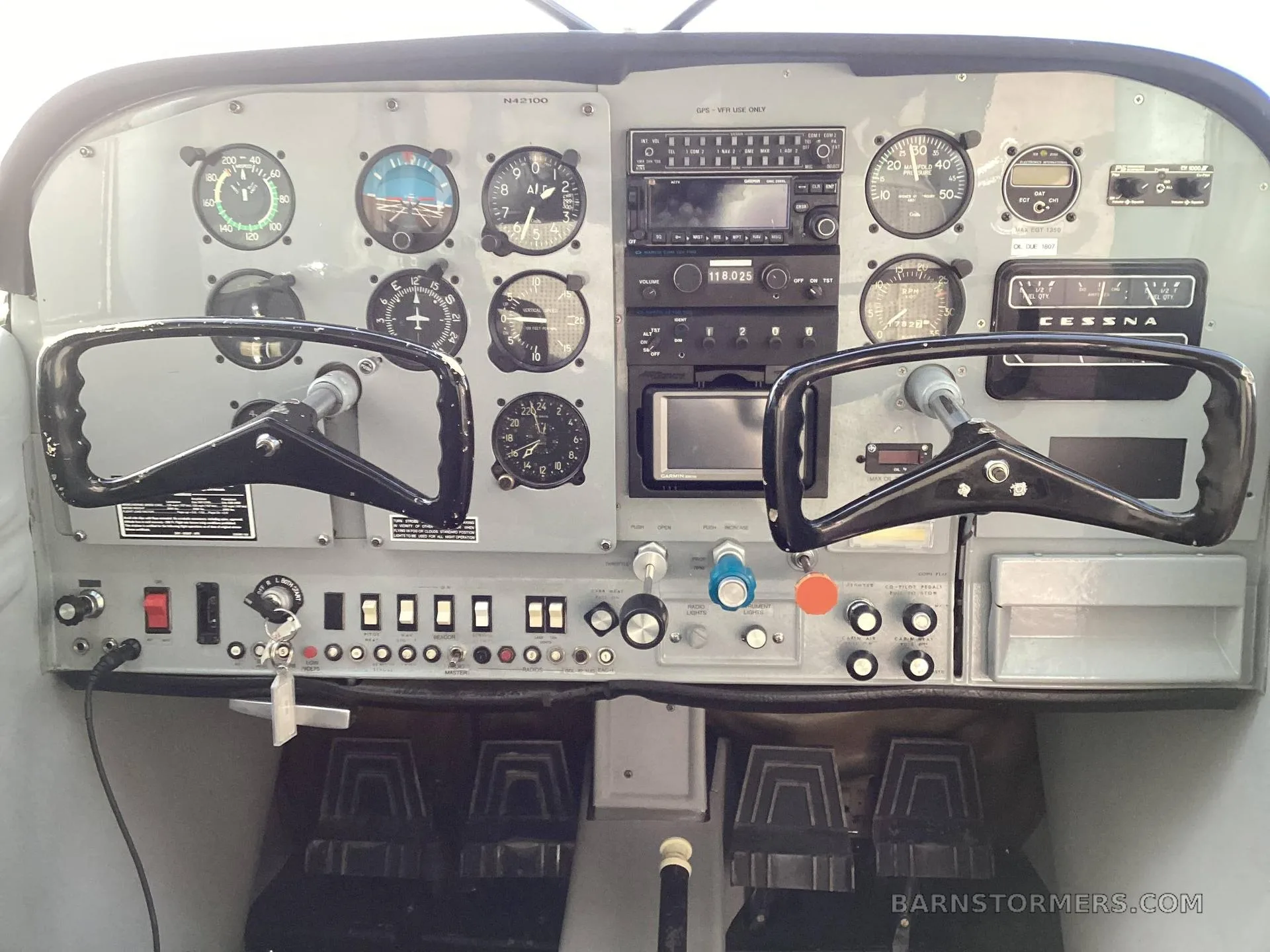 The cockpit instrument panel of a Cessna aircraft (N42100 visible on the panel) with two control yokes and various gauges.
